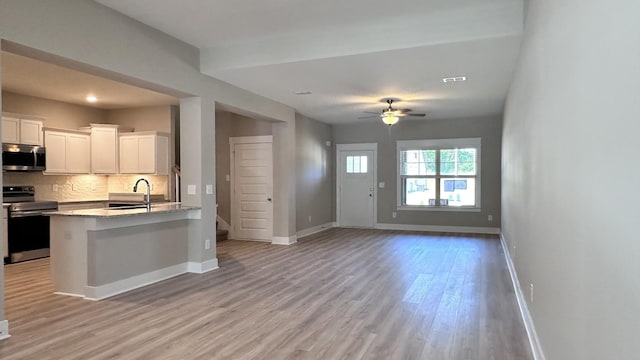 kitchen with decorative backsplash, appliances with stainless steel finishes, light stone countertops, sink, and white cabinets