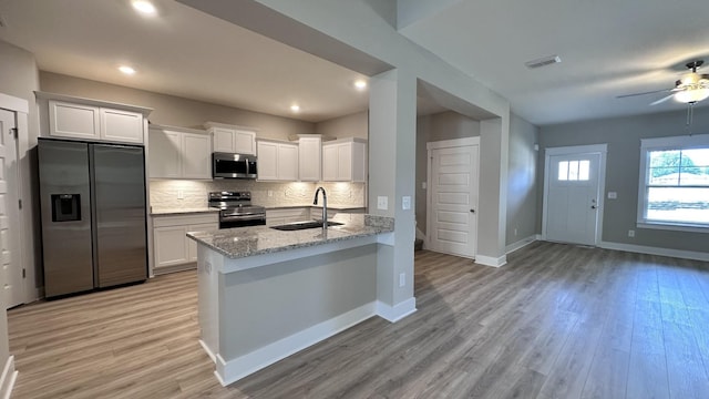 kitchen with light stone countertops, appliances with stainless steel finishes, white cabinetry, and sink