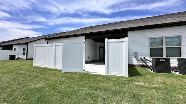 rear view of property featuring a yard and central AC