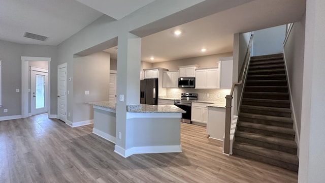 kitchen featuring backsplash, white cabinets, light hardwood / wood-style flooring, light stone counters, and stainless steel appliances