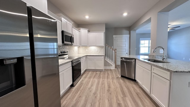 kitchen with light stone countertops, decorative backsplash, stainless steel appliances, sink, and white cabinetry