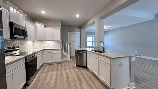 kitchen with white cabinets, sink, light stone countertops, and stainless steel appliances