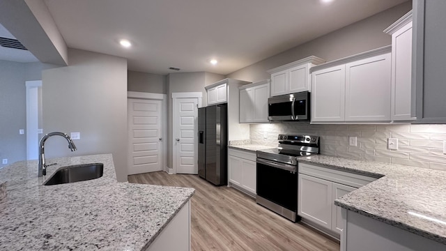 kitchen featuring backsplash, light stone countertops, white cabinets, and appliances with stainless steel finishes