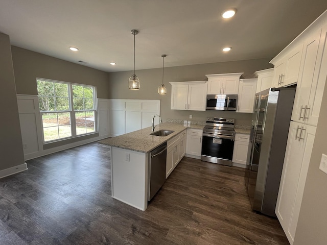 kitchen featuring sink, stainless steel appliances, light stone counters, pendant lighting, and white cabinets