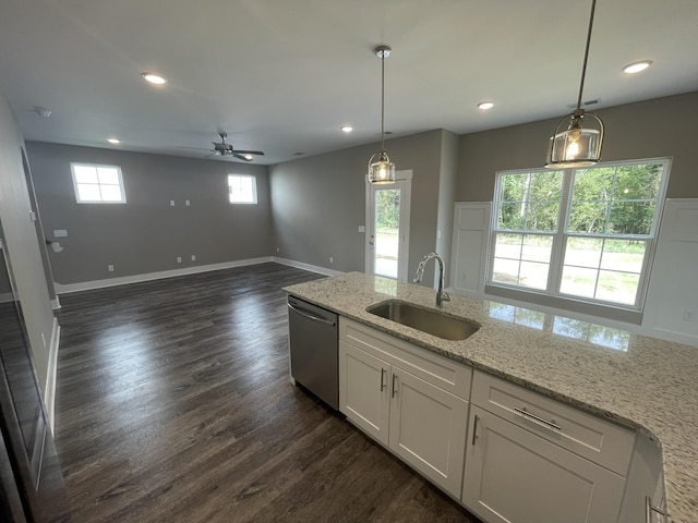 kitchen with light stone countertops, stainless steel dishwasher, sink, decorative light fixtures, and white cabinetry