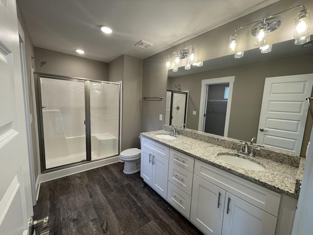 bathroom with hardwood / wood-style floors, vanity, a shower with shower door, and toilet