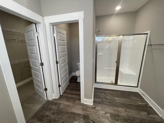 bathroom featuring a shower with door, wood-type flooring, and toilet