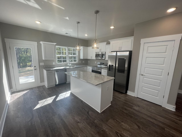 kitchen featuring white cabinets, a kitchen island, hanging light fixtures, and appliances with stainless steel finishes