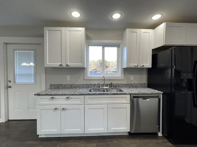 kitchen with light stone countertops, black fridge, stainless steel dishwasher, sink, and white cabinets