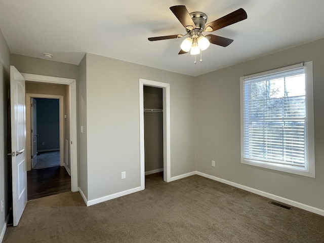 unfurnished bedroom with ceiling fan, a closet, and dark carpet