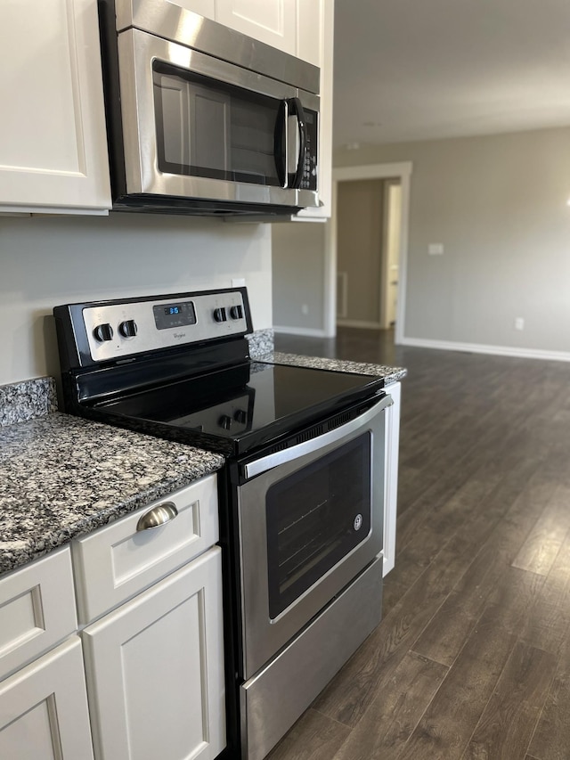 kitchen featuring white cabinets, dark hardwood / wood-style flooring, dark stone countertops, and appliances with stainless steel finishes