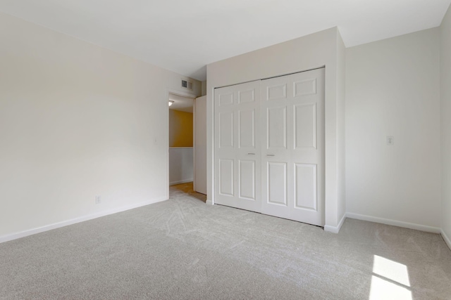 unfurnished bedroom featuring light carpet and a closet