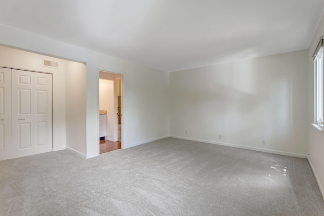 unfurnished bedroom featuring light carpet and a closet