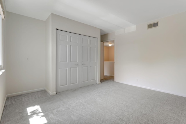 unfurnished bedroom with light carpet and a closet