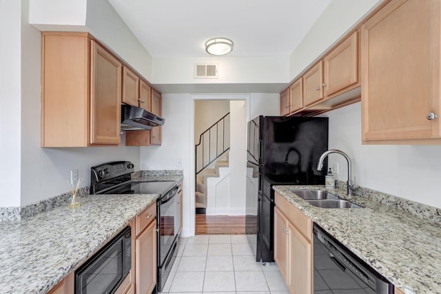 kitchen with light stone countertops, sink, light tile patterned floors, and black appliances