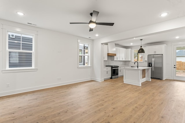 kitchen featuring a center island, premium range hood, appliances with stainless steel finishes, decorative light fixtures, and white cabinetry