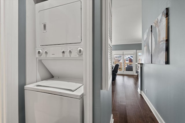 laundry area featuring dark wood-type flooring and stacked washer / drying machine