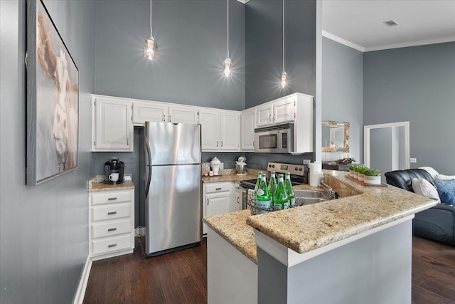 kitchen with kitchen peninsula, appliances with stainless steel finishes, a towering ceiling, light stone counters, and white cabinets