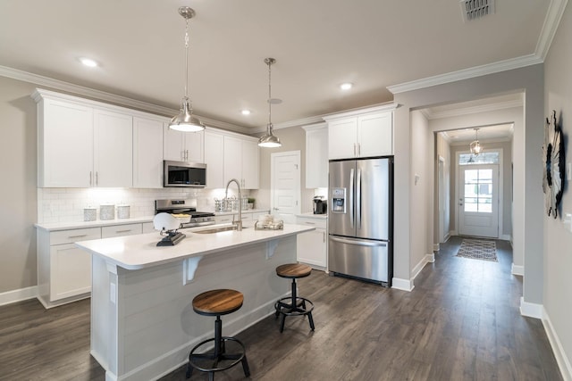 kitchen featuring white cabinetry, sink, hanging light fixtures, stainless steel appliances, and tasteful backsplash