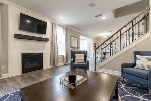 living room with hardwood / wood-style floors, ornamental molding, and a fireplace