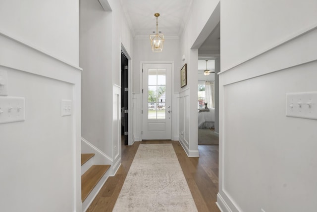 foyer featuring crown molding, baseboards, stairway, wood finished floors, and a notable chandelier