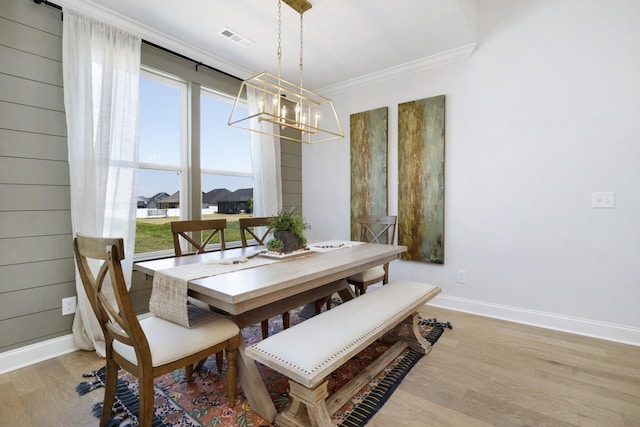 dining space featuring light wood finished floors, visible vents, crown molding, baseboards, and an inviting chandelier