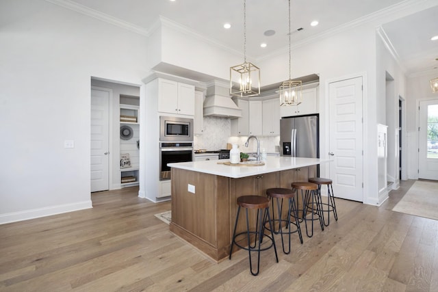 kitchen with a notable chandelier, custom range hood, a sink, tasteful backsplash, and stainless steel appliances