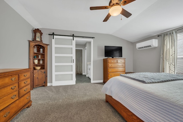 carpeted bedroom with ensuite bathroom, vaulted ceiling, a wall unit AC, ceiling fan, and a barn door