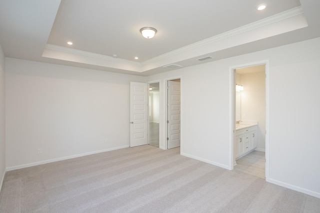 unfurnished bedroom featuring crown molding, a raised ceiling, light carpet, and ensuite bath