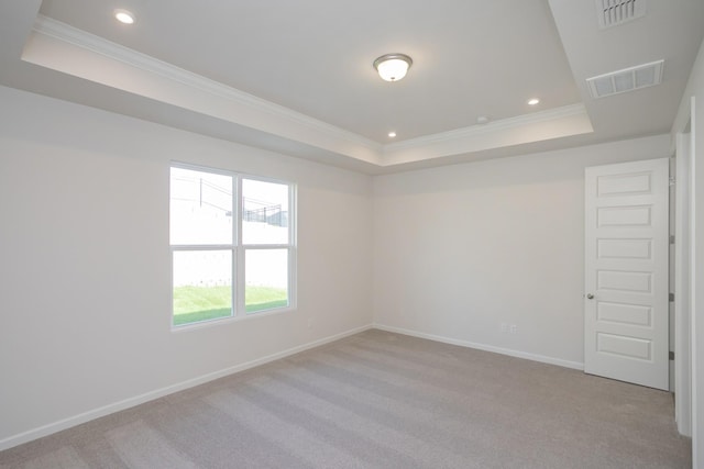 spare room featuring light carpet, a tray ceiling, and ornamental molding