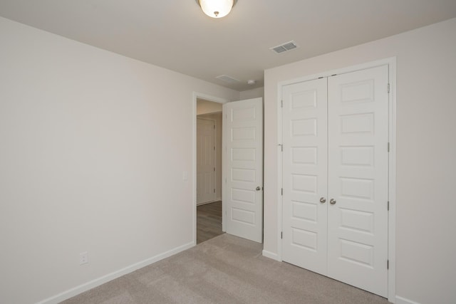 unfurnished bedroom featuring light carpet and a closet