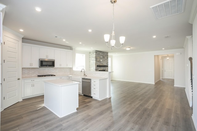 kitchen with white cabinets, a center island, stainless steel appliances, and hanging light fixtures