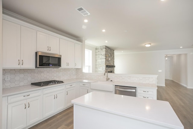 kitchen featuring white cabinets, a kitchen island, sink, and appliances with stainless steel finishes