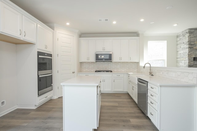 kitchen with white cabinets, sink, double wall oven, stainless steel dishwasher, and a kitchen island