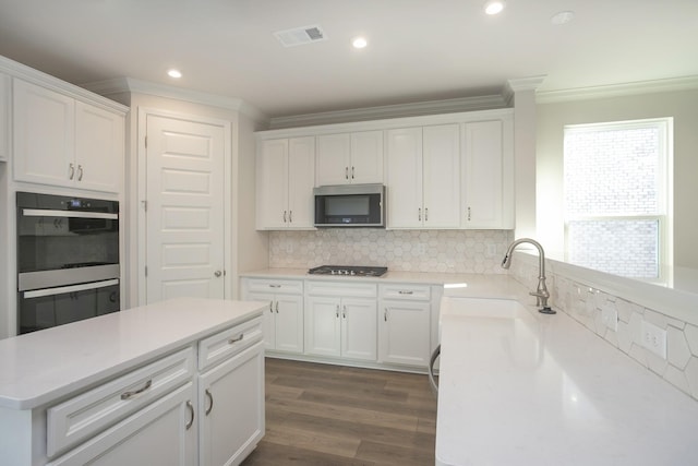 kitchen with sink, white cabinetry, stainless steel appliances, and ornamental molding