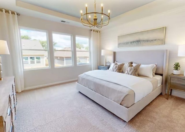 carpeted bedroom featuring a tray ceiling and a chandelier