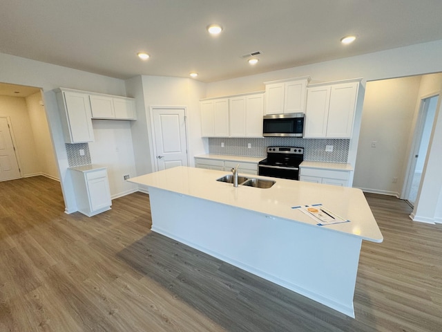 kitchen with sink, white cabinetry, backsplash, electric range, and an island with sink