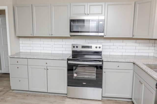 kitchen with decorative backsplash, white cabinetry, and stainless steel appliances