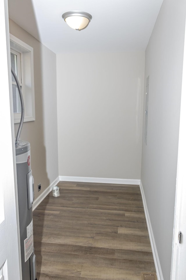 washroom featuring electric dryer hookup, water heater, and dark wood-type flooring