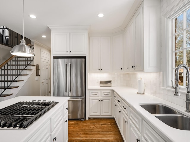 kitchen with appliances with stainless steel finishes, sink, decorative light fixtures, white cabinets, and plenty of natural light