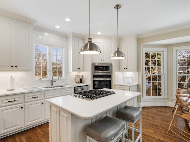 kitchen with white cabinetry, sink, a center island, pendant lighting, and appliances with stainless steel finishes