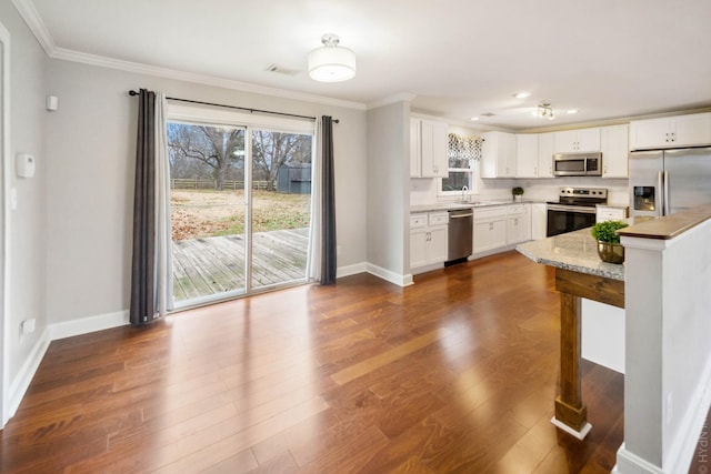 kitchen featuring sink, crown molding, appliances with stainless steel finishes, white cabinetry, and light stone counters