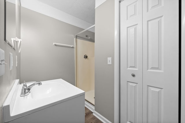 bathroom with vanity, hardwood / wood-style floors, a textured ceiling, and a shower with door