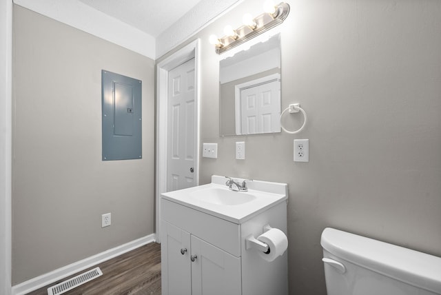 bathroom featuring a textured ceiling, vanity, hardwood / wood-style floors, electric panel, and toilet