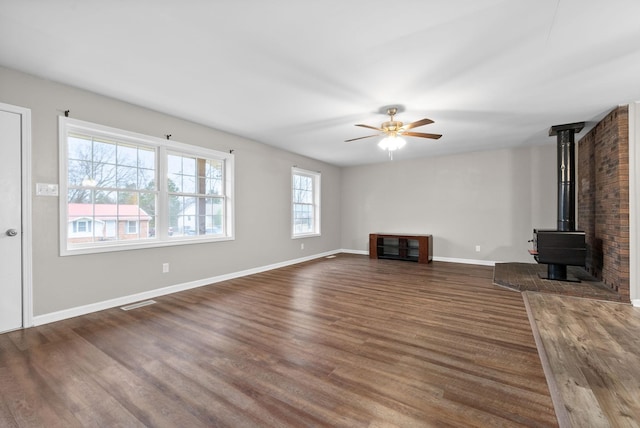 unfurnished living room with dark hardwood / wood-style floors, ceiling fan, and a wood stove