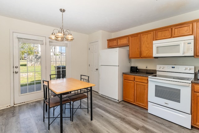 kitchen featuring decorative light fixtures, white appliances, light hardwood / wood-style flooring, and an inviting chandelier