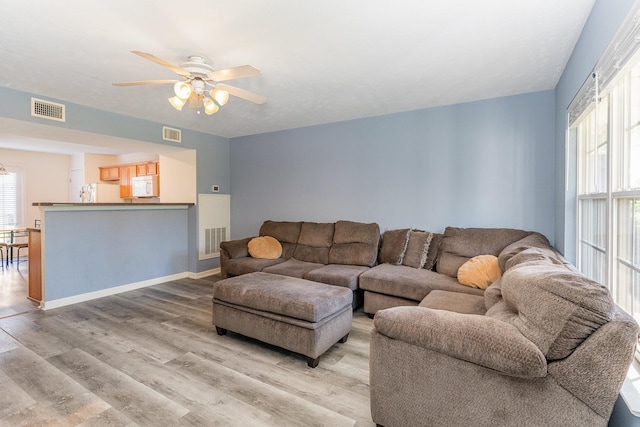 living room with a wealth of natural light, light hardwood / wood-style flooring, and ceiling fan