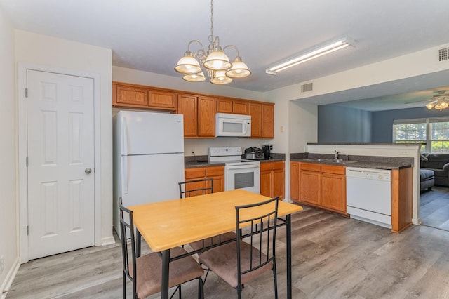 kitchen featuring ceiling fan with notable chandelier, hanging light fixtures, white appliances, and light wood-type flooring