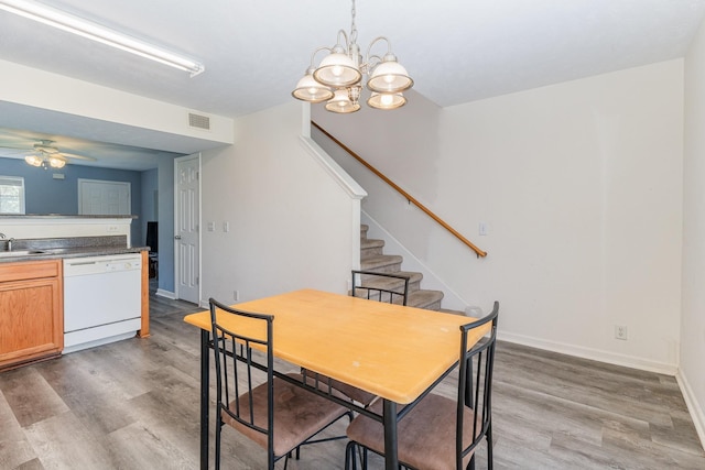 dining area with sink, dark wood-type flooring, and ceiling fan with notable chandelier