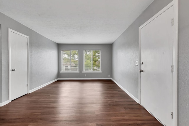 unfurnished room with a textured ceiling and dark hardwood / wood-style floors